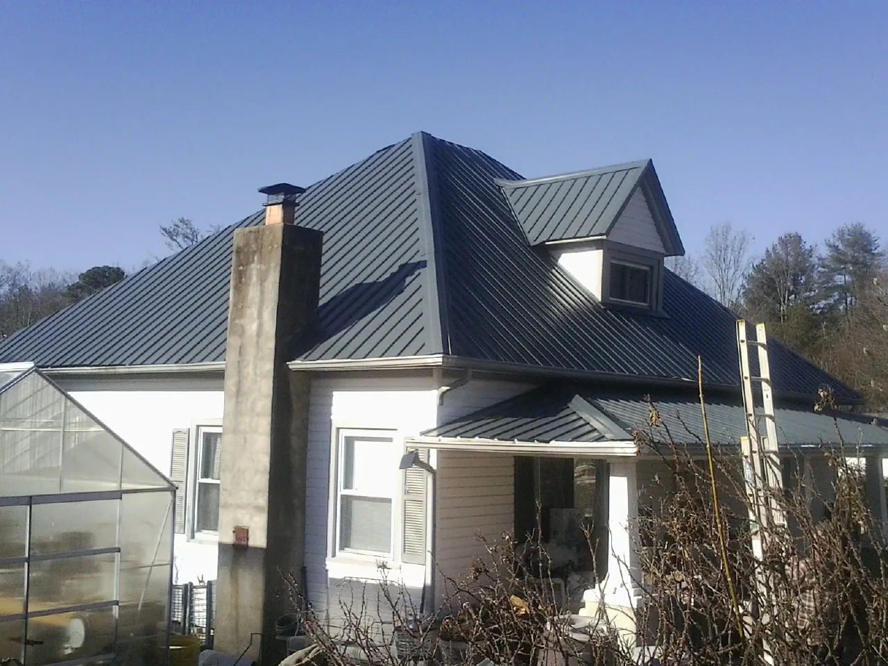 Dark blue standing seam metal roof on a white farmhouse with dormer — Slate & Tile Roof Repair by Roofing Brothers in Granbury