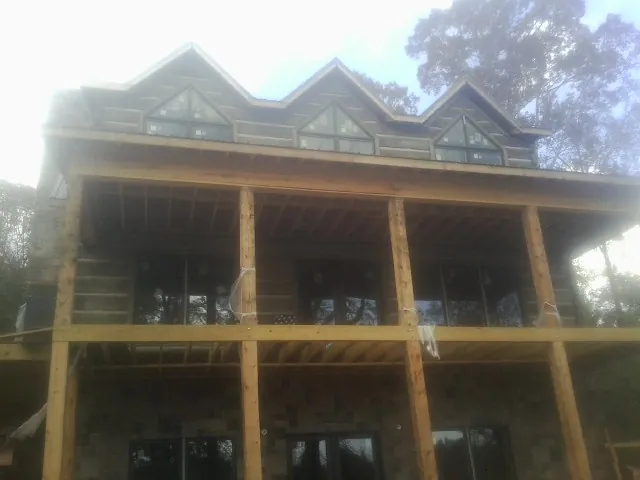 Dormers and porch framing on a large log home under construction — Roof Coating work by our crew in Granbury
