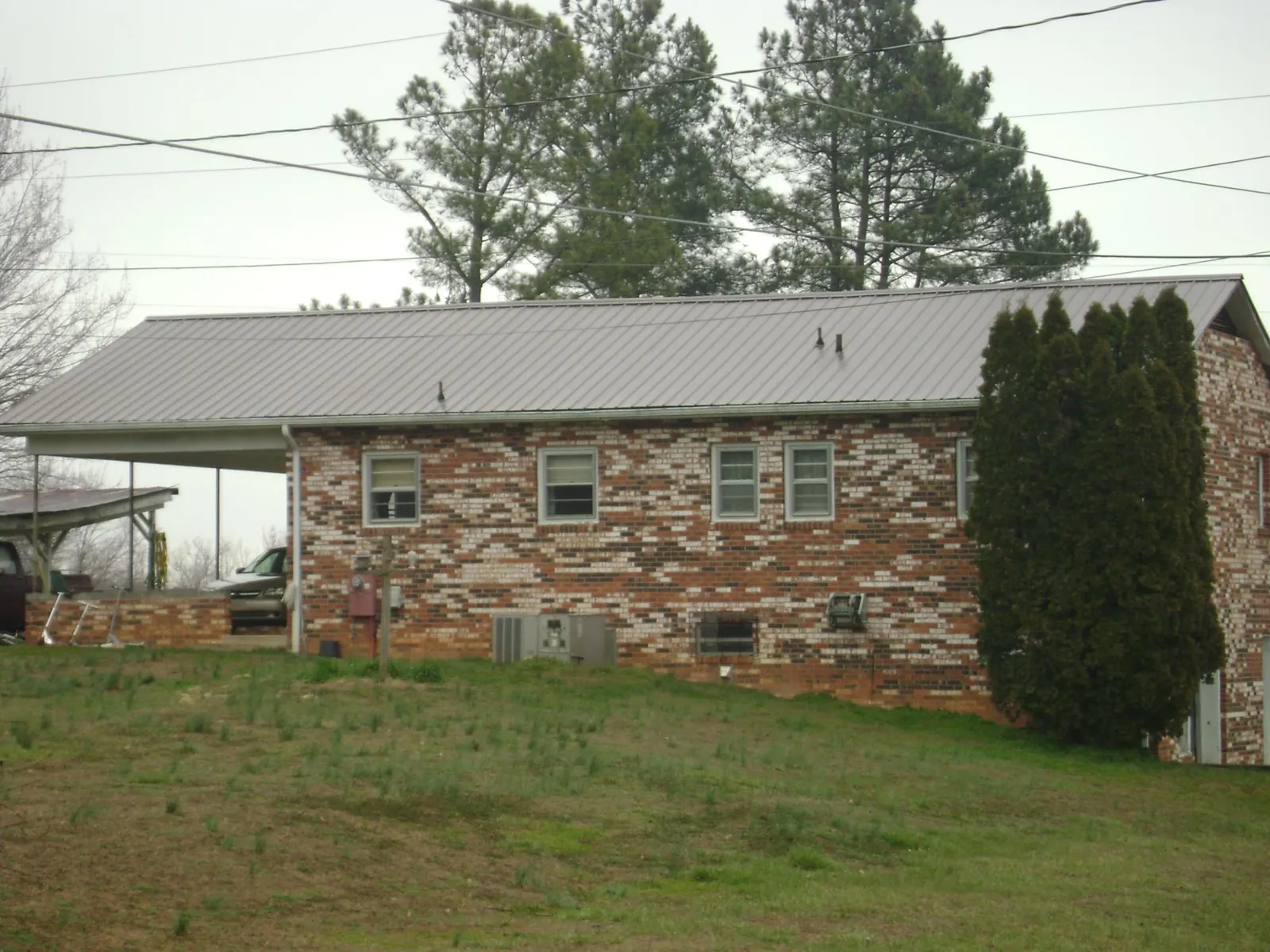 Gray metal roof on a brick split level home with a carport in Granbury