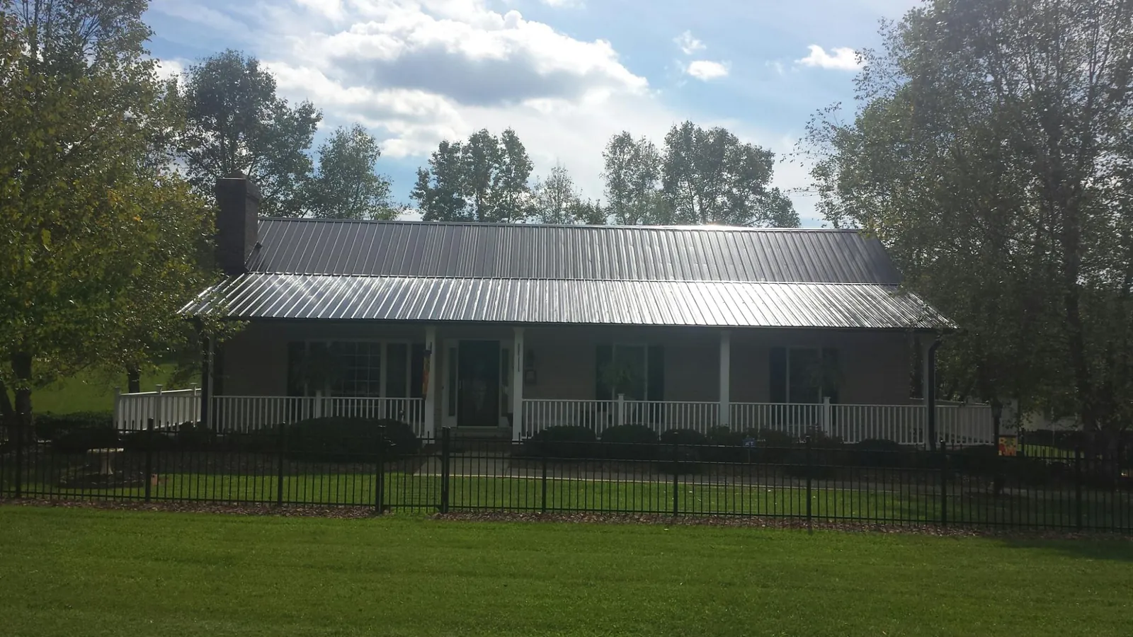 Gray metal roof on a brick ranch with a full width front porch — Gutter Guard Installation work by our crew in Granbury
