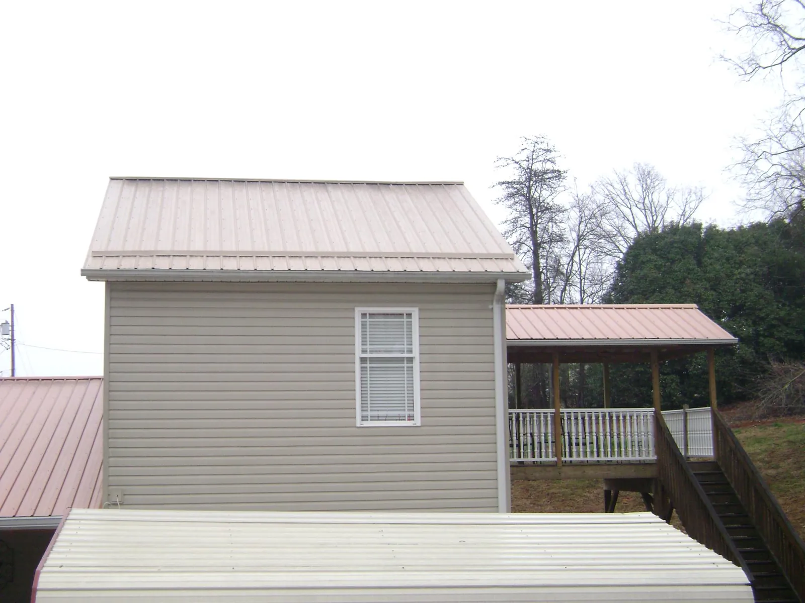 Tan metal roofs on a two story addition and attached porch, from a Roof Replacement job in Granbury