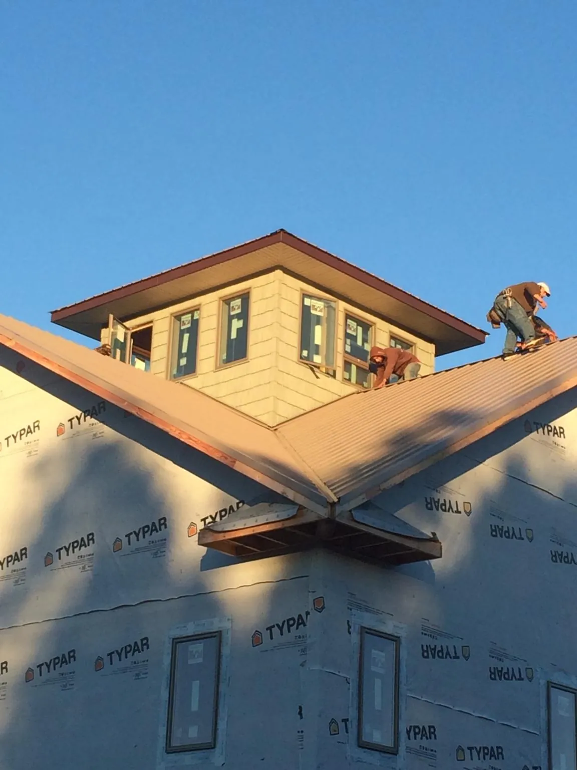 Roofers working around a rooftop cupola on a new metal roof at sunset — Roof Waterproofing in Granbury by Roofing Brothers